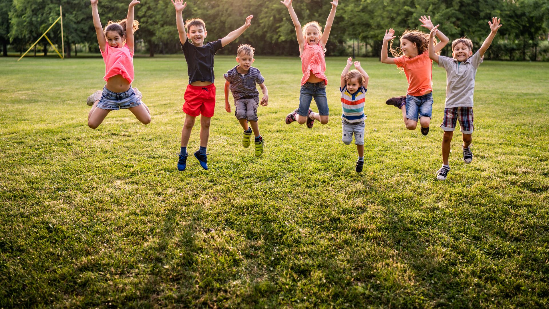 Children jumping on green grass
