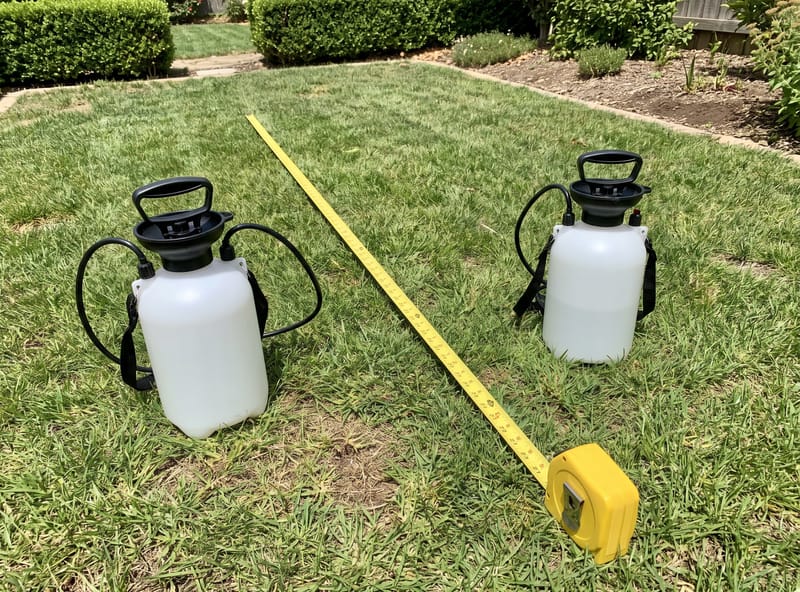 Tape measure on lawn with pump sprayer — measuring lawn area for coverage calculation